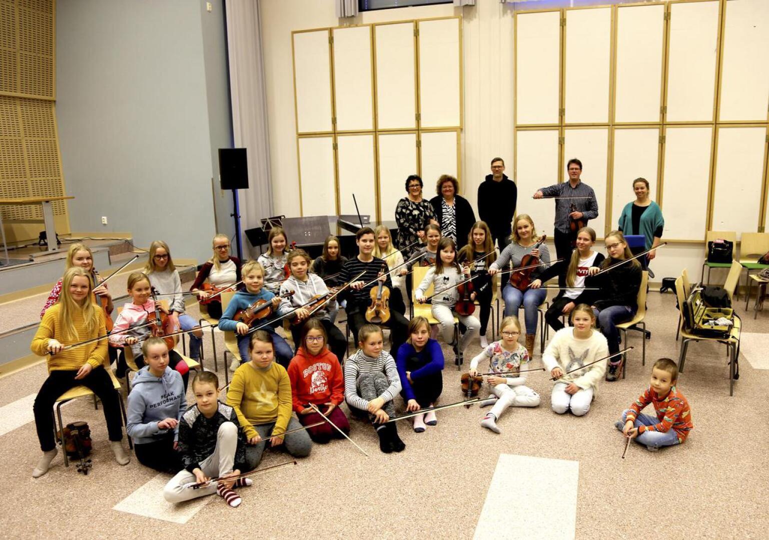 Keski-Pohjanmaan konservatoriossa viulun perusopetuksessa olevia oppilaita sekä taustalla opettajat. Janne Malmivaaralla kädessään jousi. 