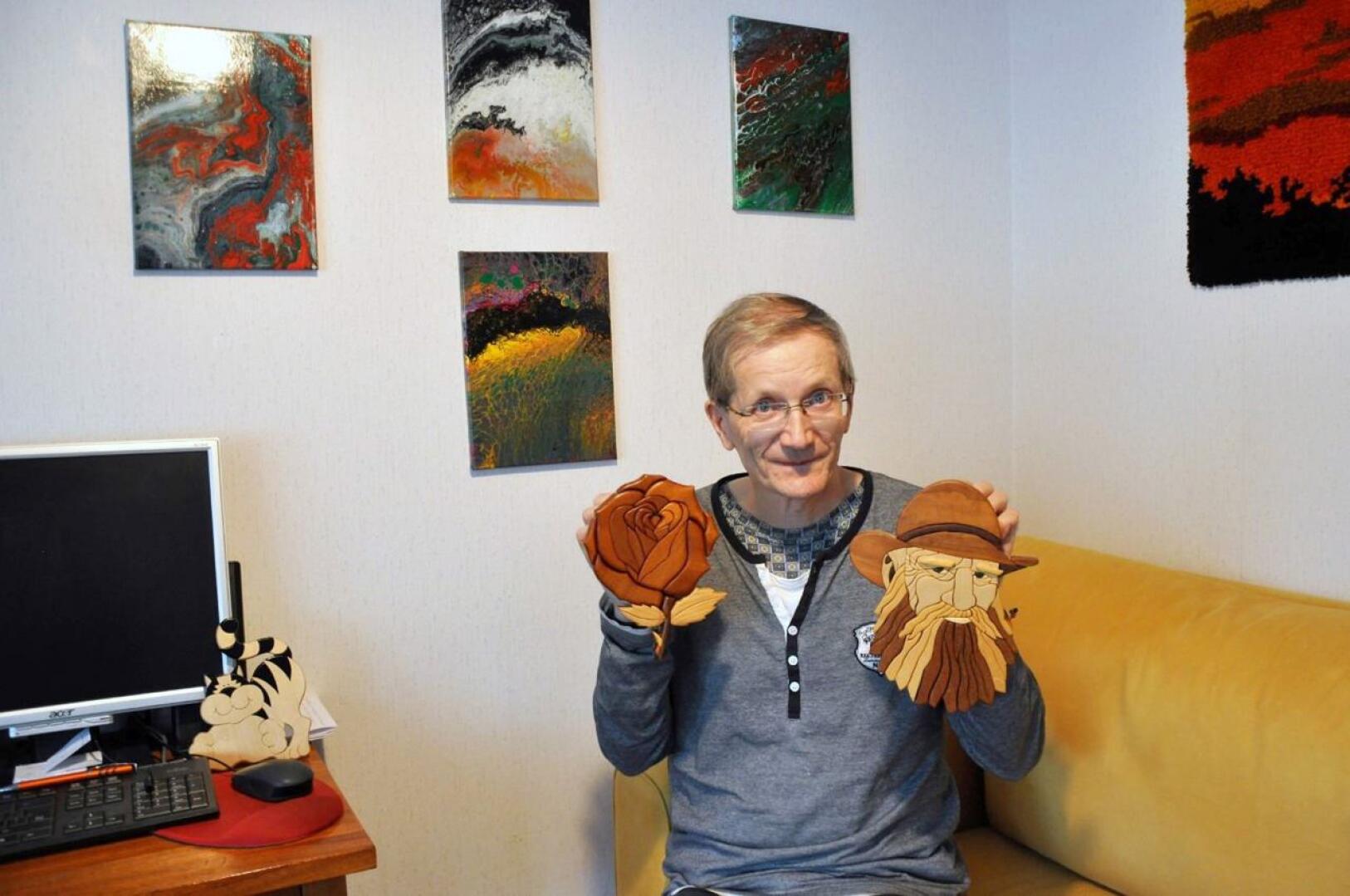 Heikki Moilanen tekee muun muassa eri puulajeja yhdistelmällä tauluja. Seinällä näkyy hänen akryylitöitään.