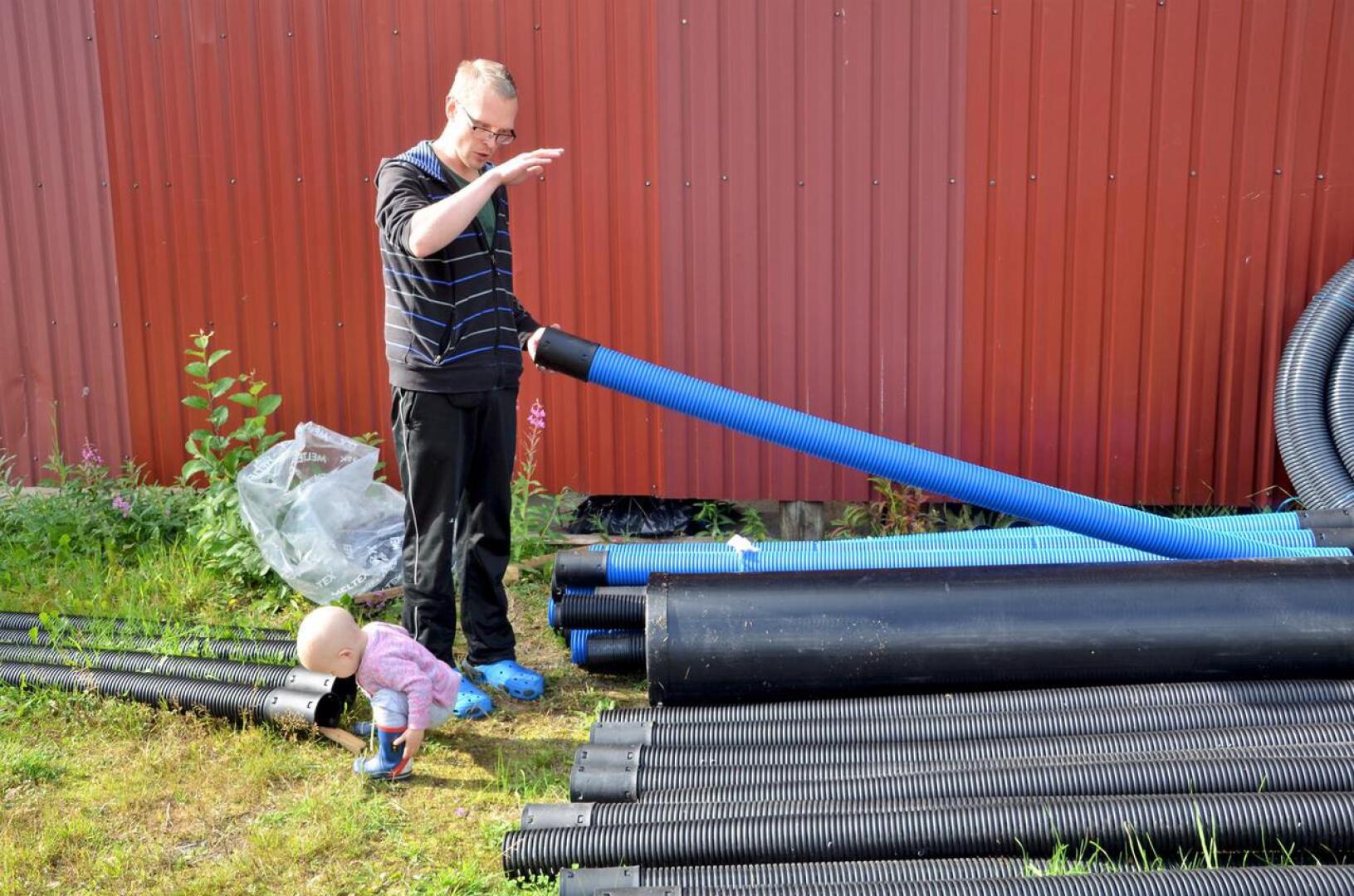 Antti Lagerbohm esittelee hänen ja vaimonsa Jenni Kentalan pihaan Halsualla tulevaa jätevesijärjestelmää. Myös Julia-tytär tarkastaa putkia.