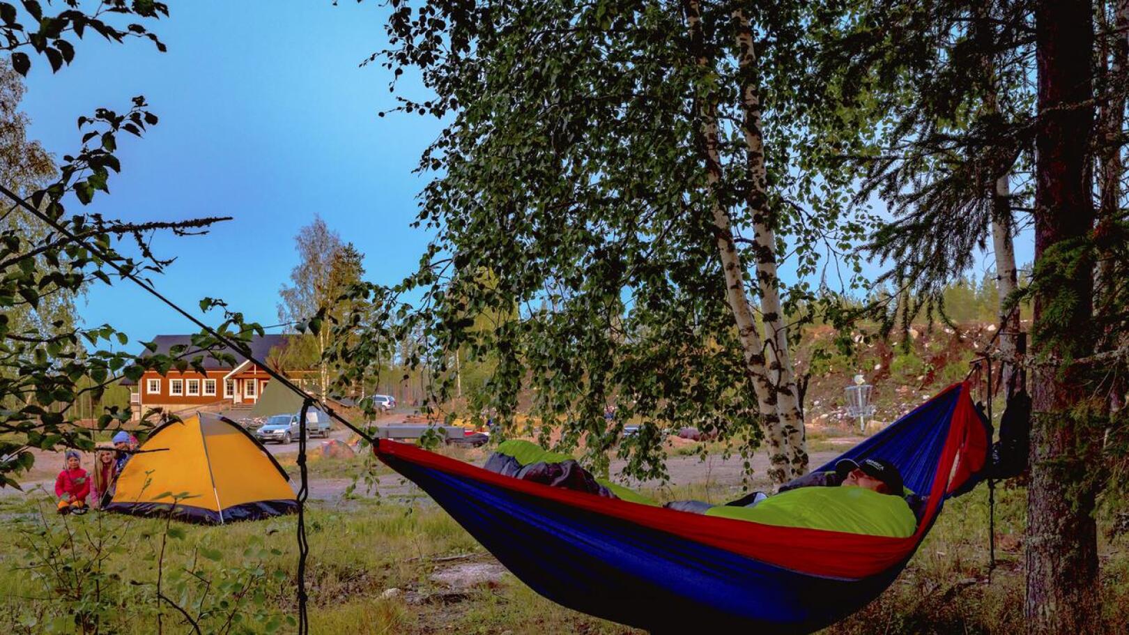 Riippumattoon on asettautunut Lauri Penninkangas, taustalla telttayöhön valmistautumassa Anni ja Aino Karvosenoja, Vilma Aho ja Viola Penninkangas.