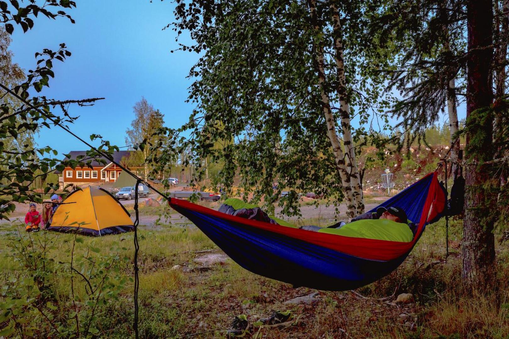 Riippumattoon on asettautunut Lauri Penninkangas, taustalla telttayöhön valmistautumassa Anni ja Aino Karvosenoja, Vilma Aho ja Viola Penninkangas.