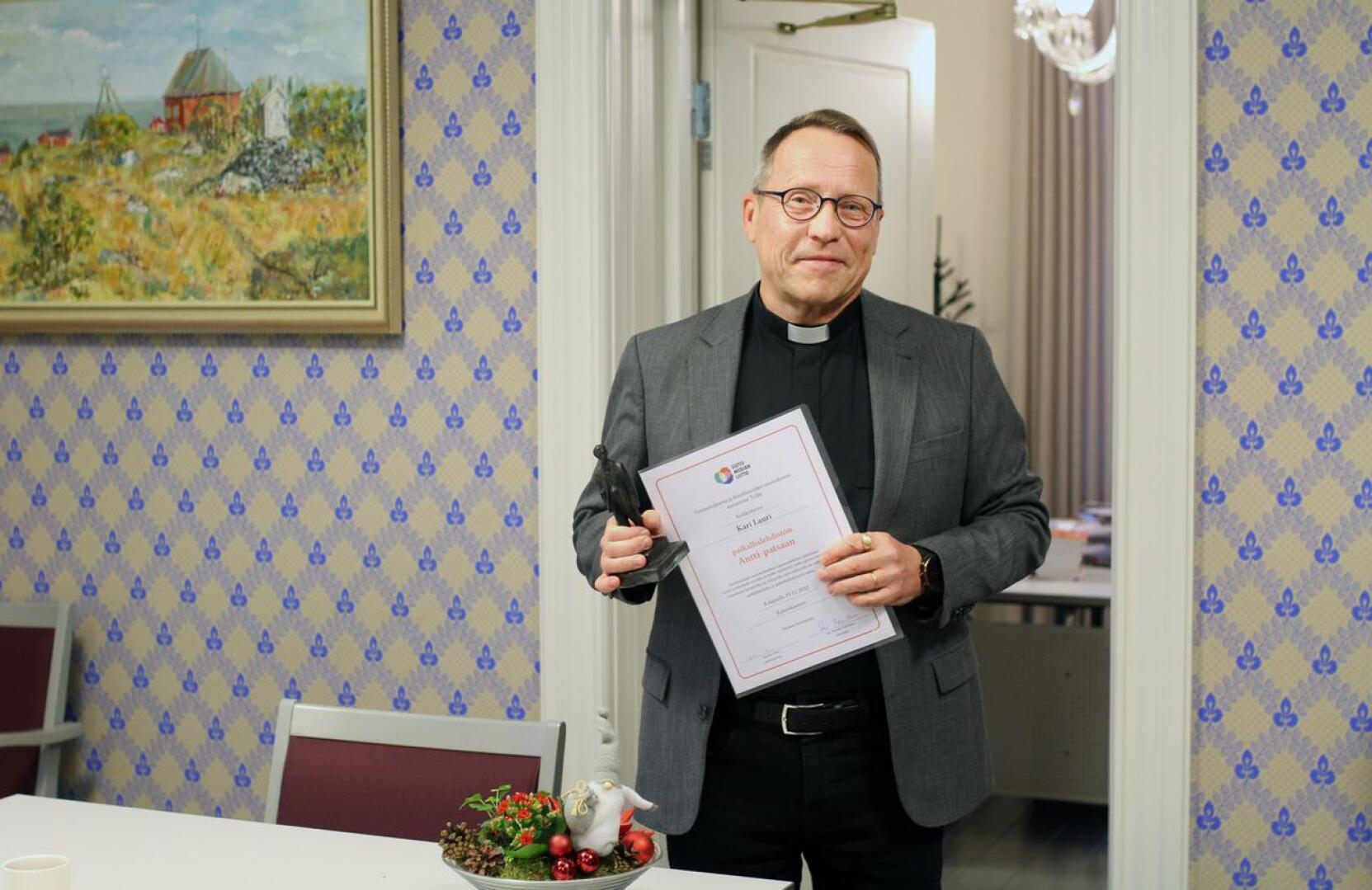 Kirkkoherra Kari Lauri sai lehden Antti-patsaan hyvästä yhteistyöstä ja tiedottamisesta.