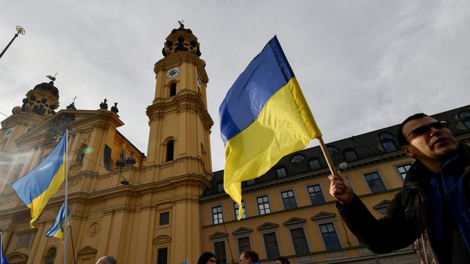 Ukrainalaiset eri ammateissa ja eri tasoilla tekevät hartiavoimin töitä saadakseen äänensä kuuluviin. Turvallisuuskonferenssin ulkopuolella Saksassa nainen piteli Ukrainan lippua osana mielenosoitusta Ukrainan tukemiseksi 15. helmikuuta.