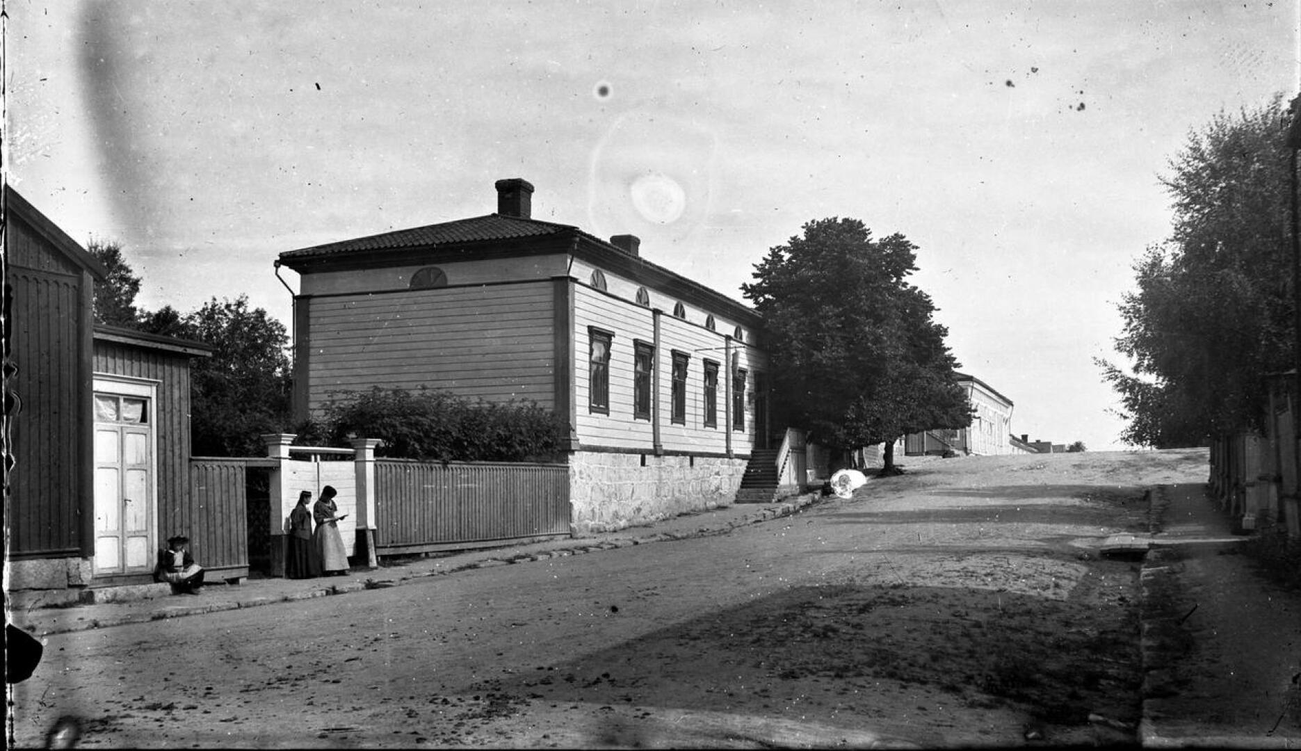 Kuva  vuodelta 1900, jolloin suutari asui ns. Irjalan talossa. Talon ulkopuolella näkyy myös saapas mikä kertoo että talossa on suutari. Kuvan on ottanut Aage Andreasen. 