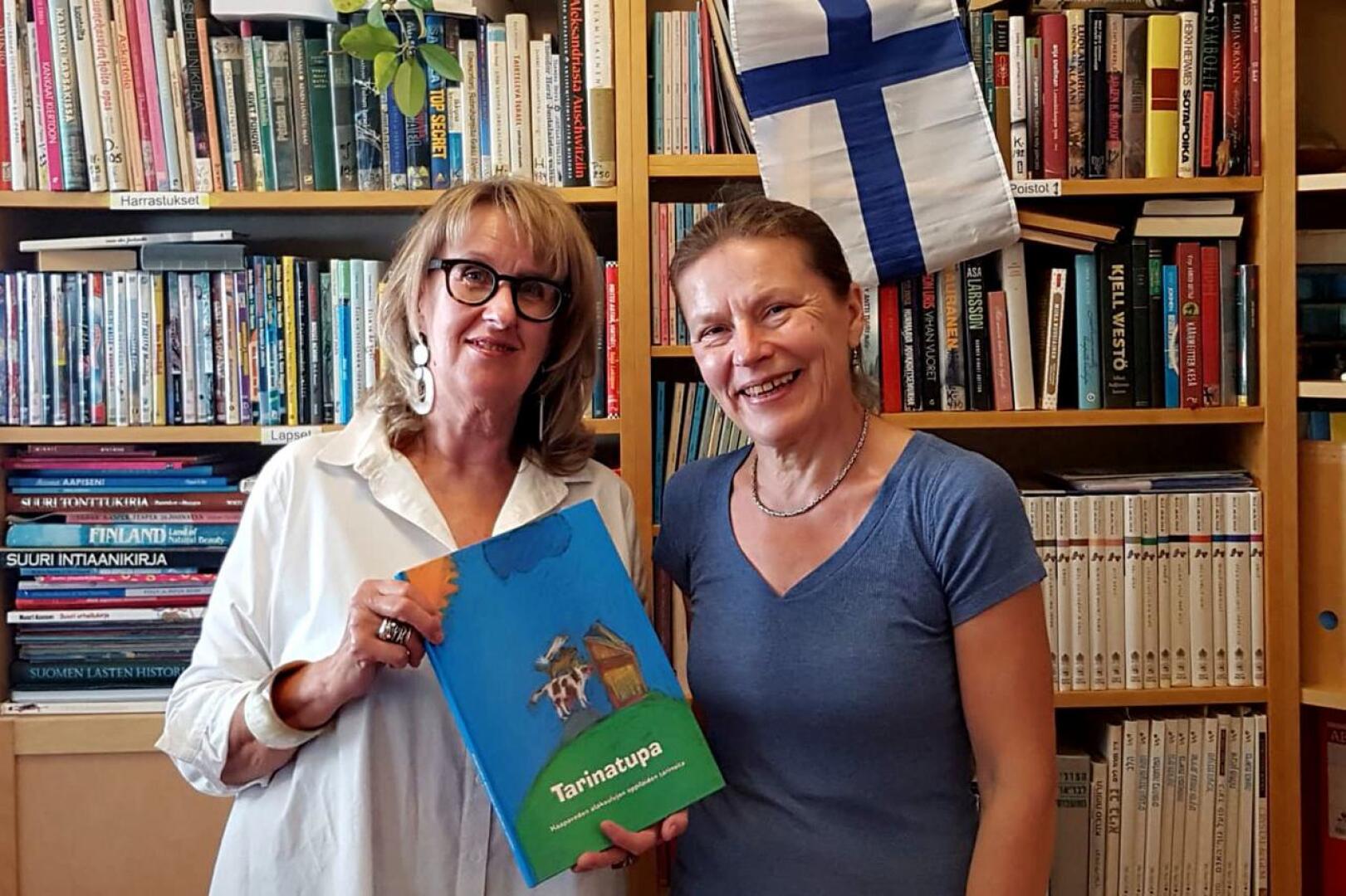 Kirjastonhoitaja Anu Morchy Levi (oikealla) otti ilolla vastaan Tarinatupa -kirjan, jonka Anneli Repo toi terveisinä Haapaveden kirjastolta Israelin Suomi-kirjastoon.