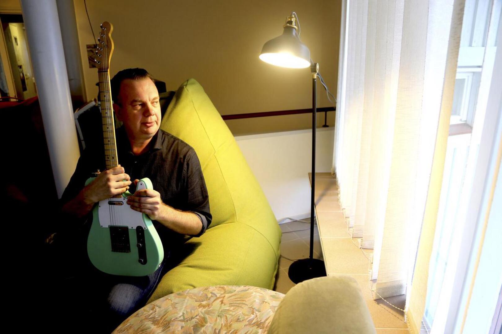 Rasmus Tammik opettaa musiikkia musiikkilukiossa ja on parin vuoden ajan harrastanut soitinten entisöintiä. Sylissään olevan vihreän kitaran hän on koonnut osista käyttöönsä. 