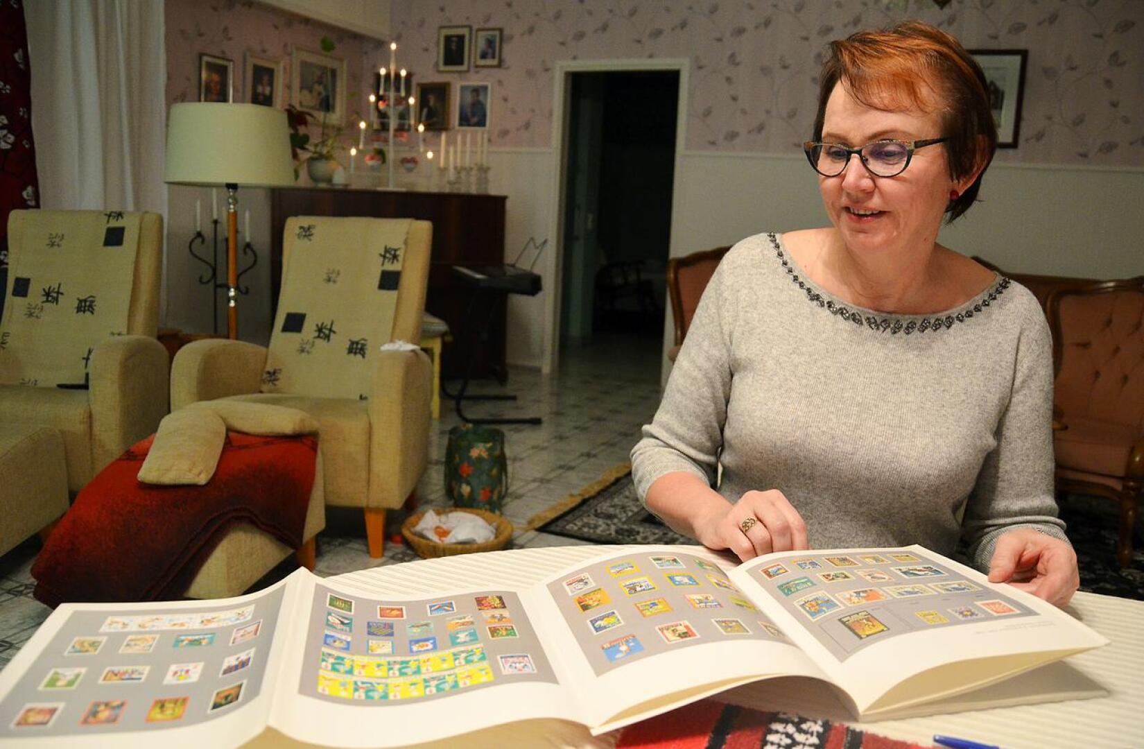 Joulumerkkikodissa oloajasta ovat jääneet mukavat muistot Heli Mattilalle. Kuvassa hän selaa kirjaa, jossa on eri vuosien joulumerkkejä. Niiden myynnillä rahoitettiin kodin toimintaa.