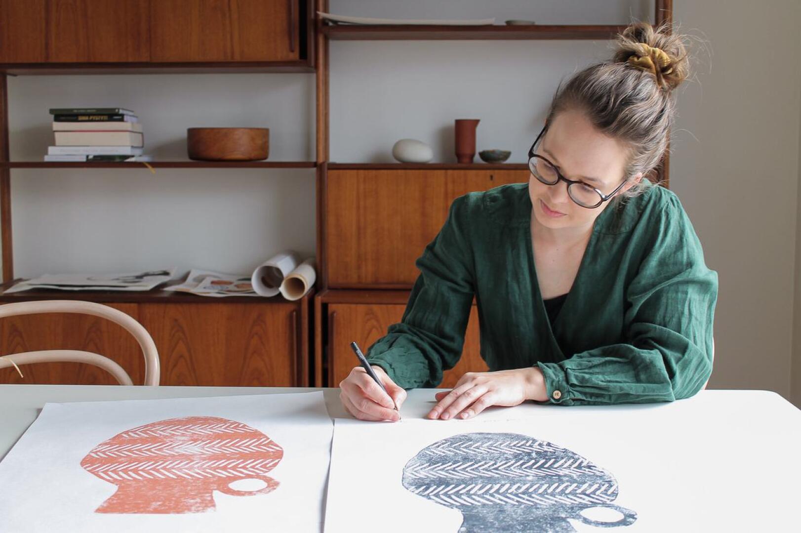 Muotoilija Sari Viljamaa signeeraamassa käsinpainettua taidejulistetta.