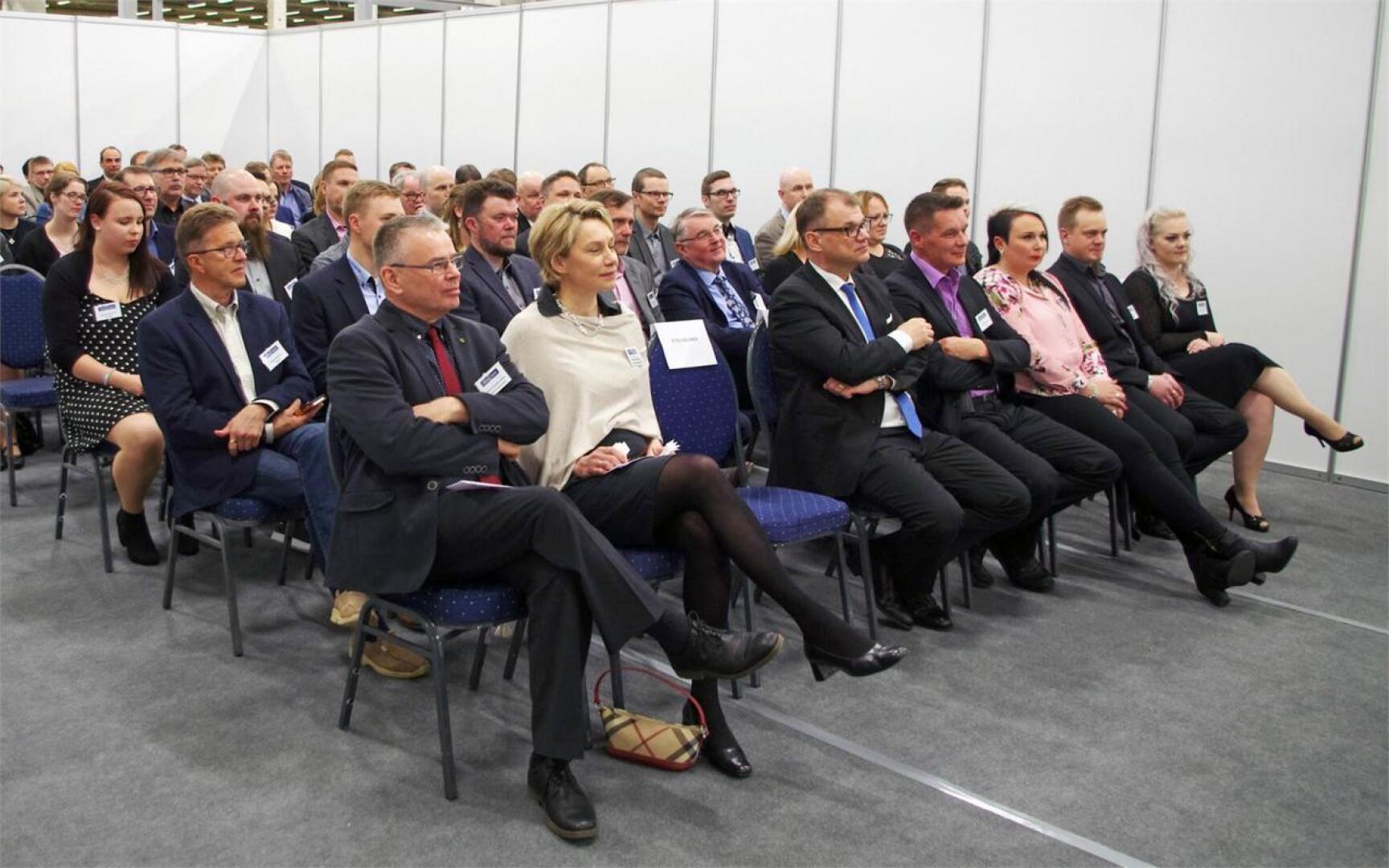 Uuteen eristyslasitehtaaseen tutustuivat avajaisissa myös pääministeri Juha Sipilä ja Nivalan kaupunginjohtaja Päivi Karikumpu (eturivi kolmantena ja toisena vasemmalta).