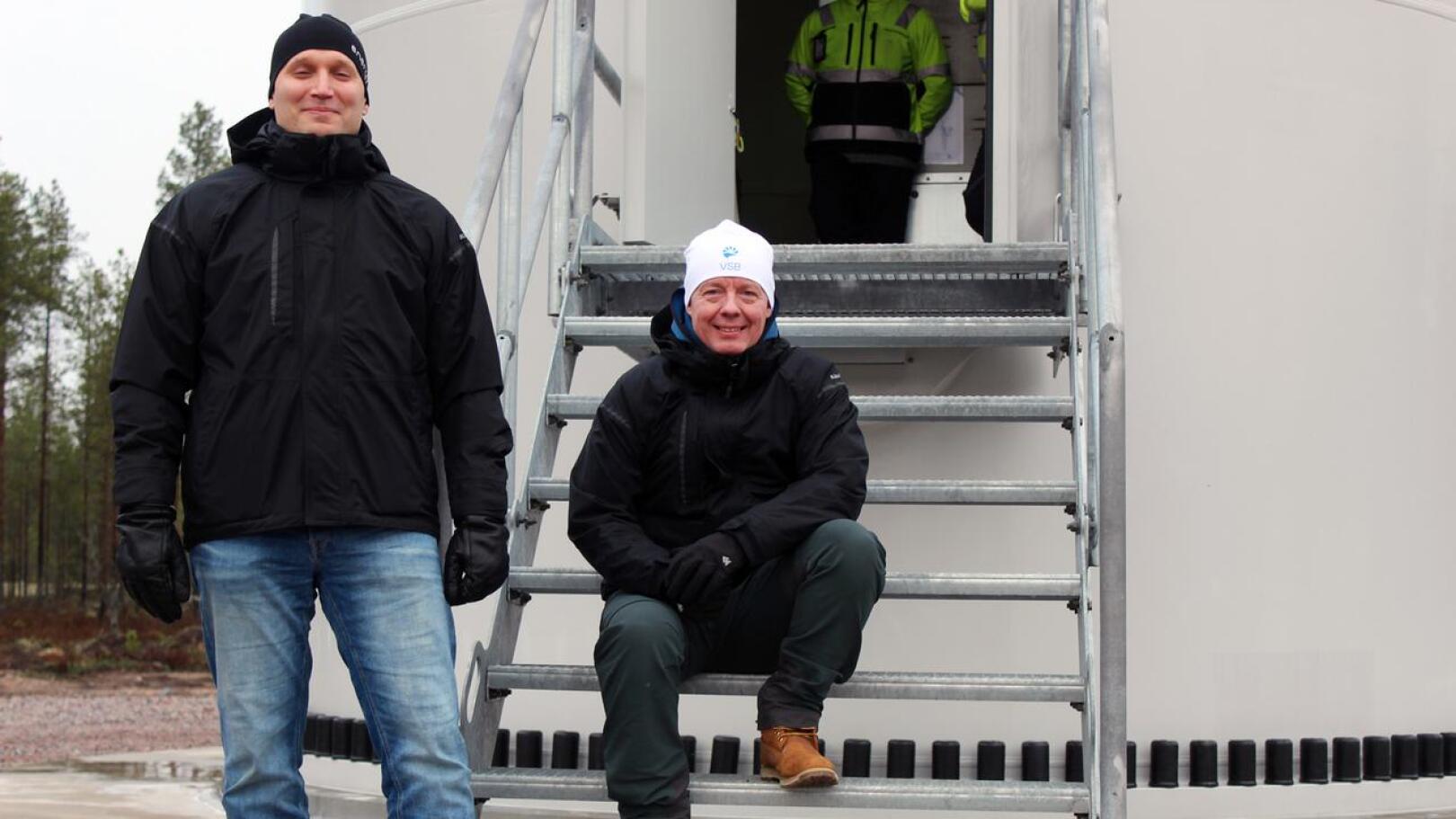 VSB -konsernin miehet, Suomen rakentamisjohtaja Sami Orajärvi ja Uusiutuva Energia Suomi Oy:n toimitusjohtaja Seppo Tallgren huokaisevat tyytyväisyydestä Juurakon tuulipuiston valmistuttua ajallaan. Taustalla yksi seitsemästä turbiinista, jolla on korkeutta 230 metriä.