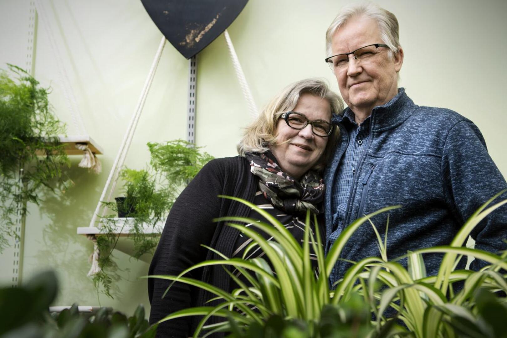 Hautausalan yrittäjät Riitta ja Reijo Laurila ovat kasvaneet työhönsä yrittäjävuosien aikana. Taustalla näkyy perinteinen kasvi unelma eli plumosus.