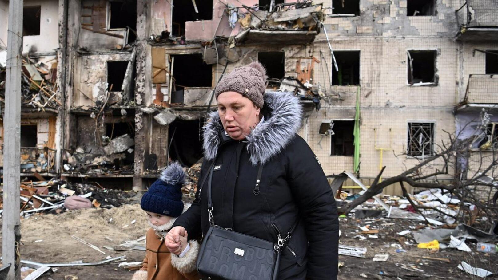Nainen ja pikkuktyttö kävelemässä tykistöammusten perjantaina tuhoamalla kadulla Kiovassa.