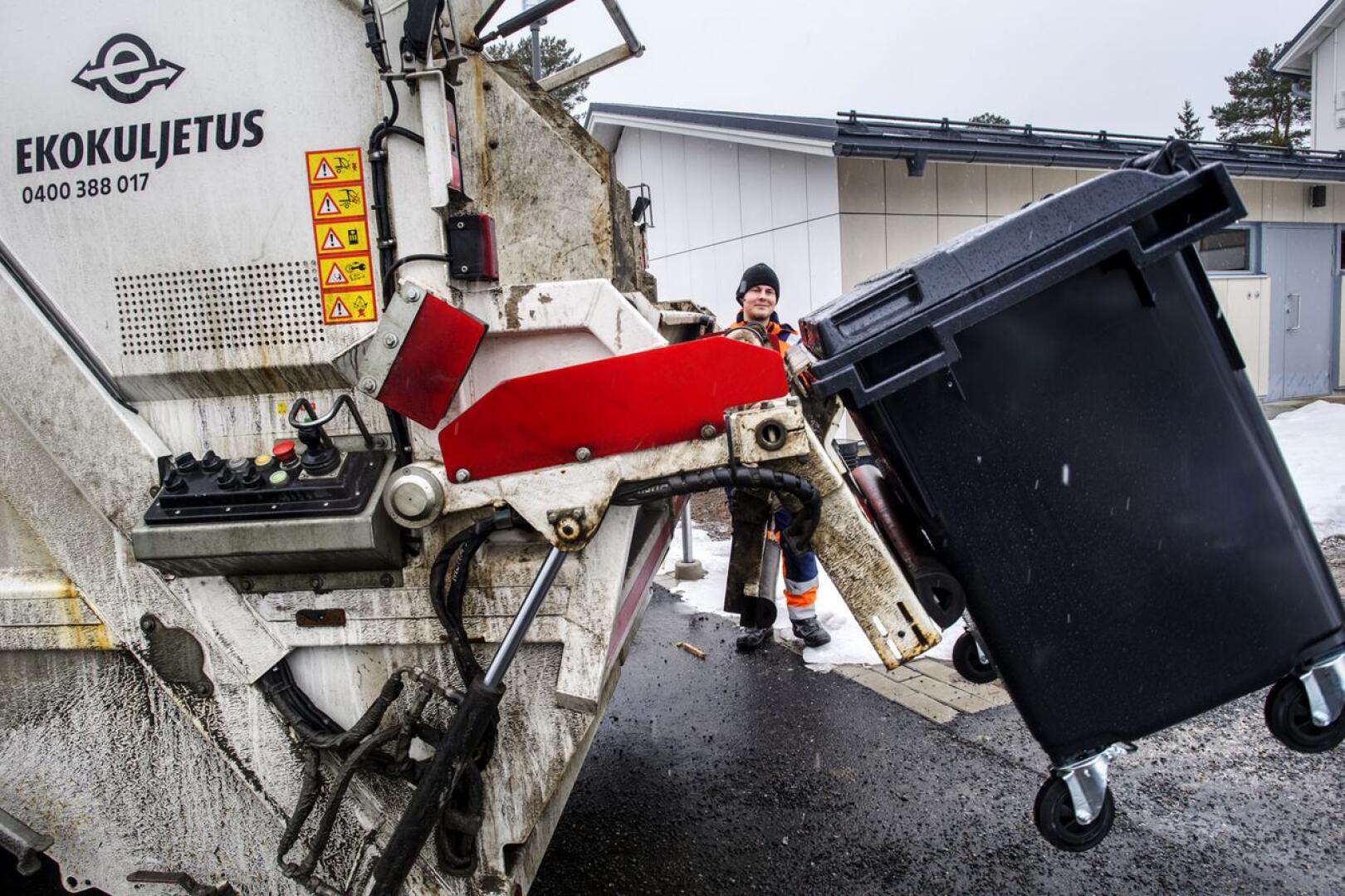 Jäteauton kuljettaja Toni Paananen tyhjensi jäteastioita Kokkolassa maanantain tihkusateessa.