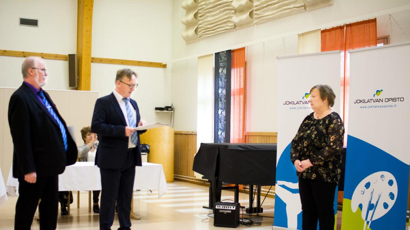 Haapajärven kaupungin sivistysjohtaja Veijo Tikanmäki (vas.) ja Jokilatvan rehtori Kim Oja ojensivat Ulla Tiitolle kaksi ansiomerkkiä.