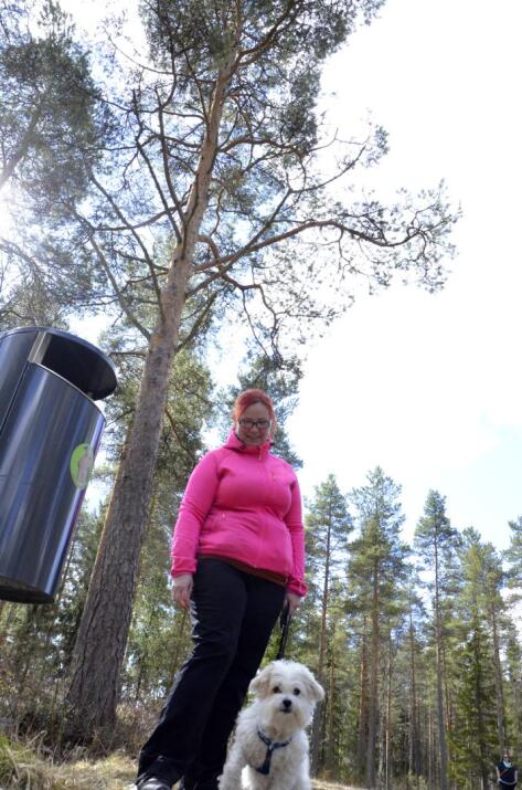 Lenkkeilevät Eija-Liisa Pokki ja Onni-koira on hyvillään, että metsäkerholaiset ovat masinoineet roskiksia pururadan varteen.