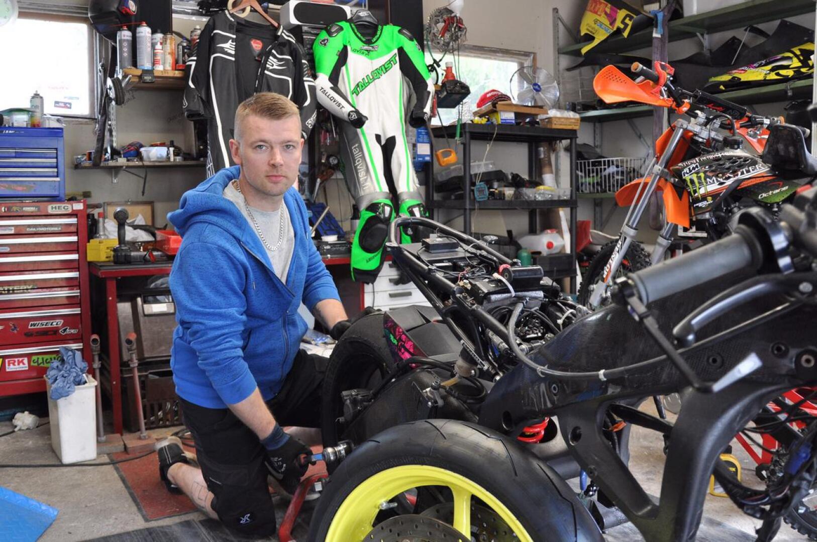 Miika Viiperi vaihtaa moottoripyörään rengasta isänsä autotallissa. 