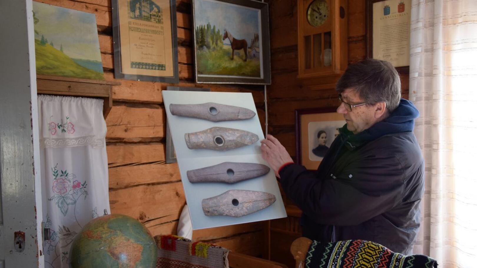 Juhani Alaranta esittelee kuvaa vasarakirveistä, jollaiset löytyivät 1930-luvulla Merijärveltä löydetystä kivikautisesta kaksoishaudasta. Alarannan ansiot kotiseututyössä ovat paikallisia.