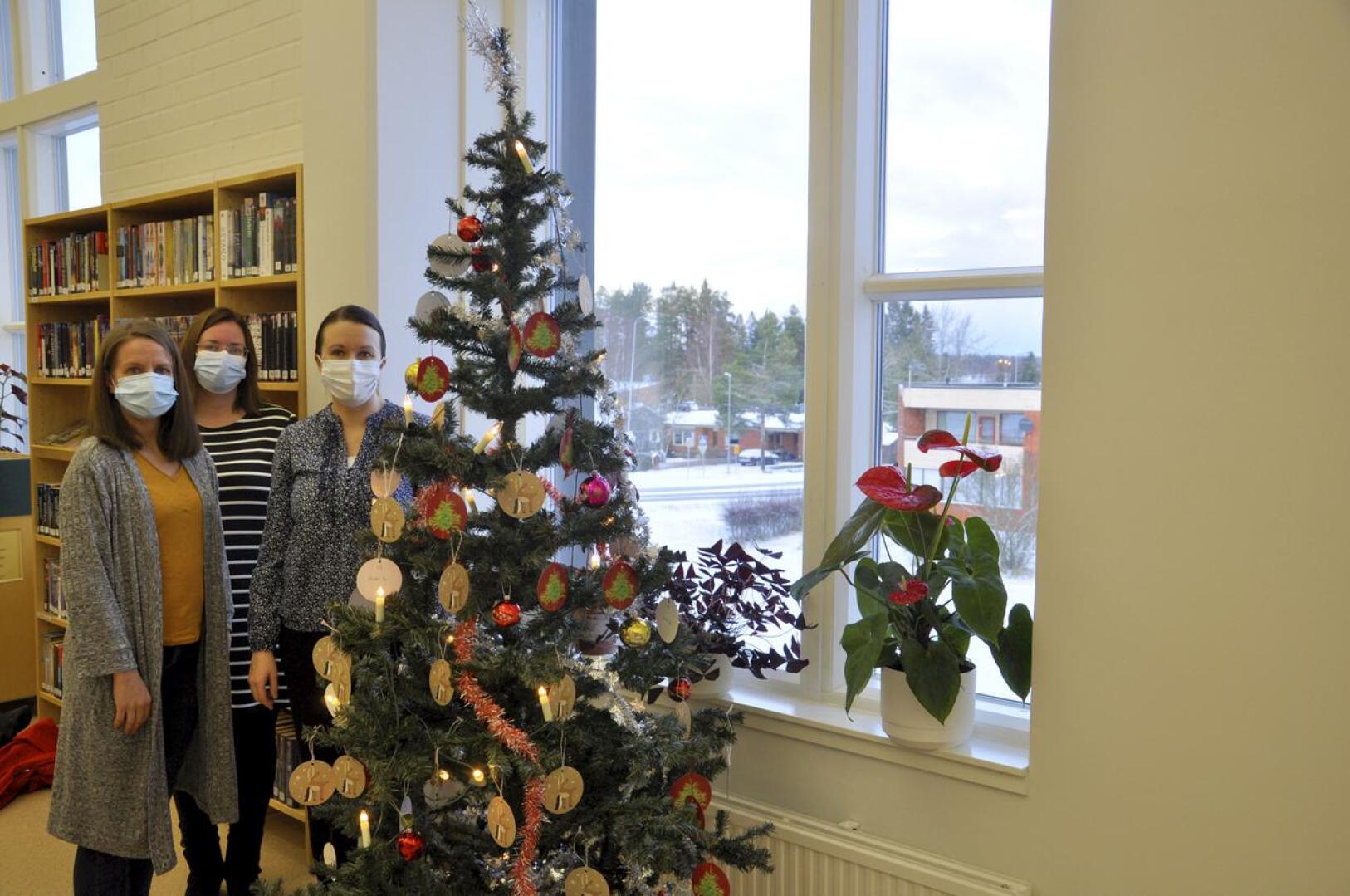 Toholammin joulupuu. Tiina Keskisipilä, Anniina Lintilä ja Anu Ahokas toivat pakettikortteja Joulupuu-keräyksen kuuseen Toholammin kirjastoon.