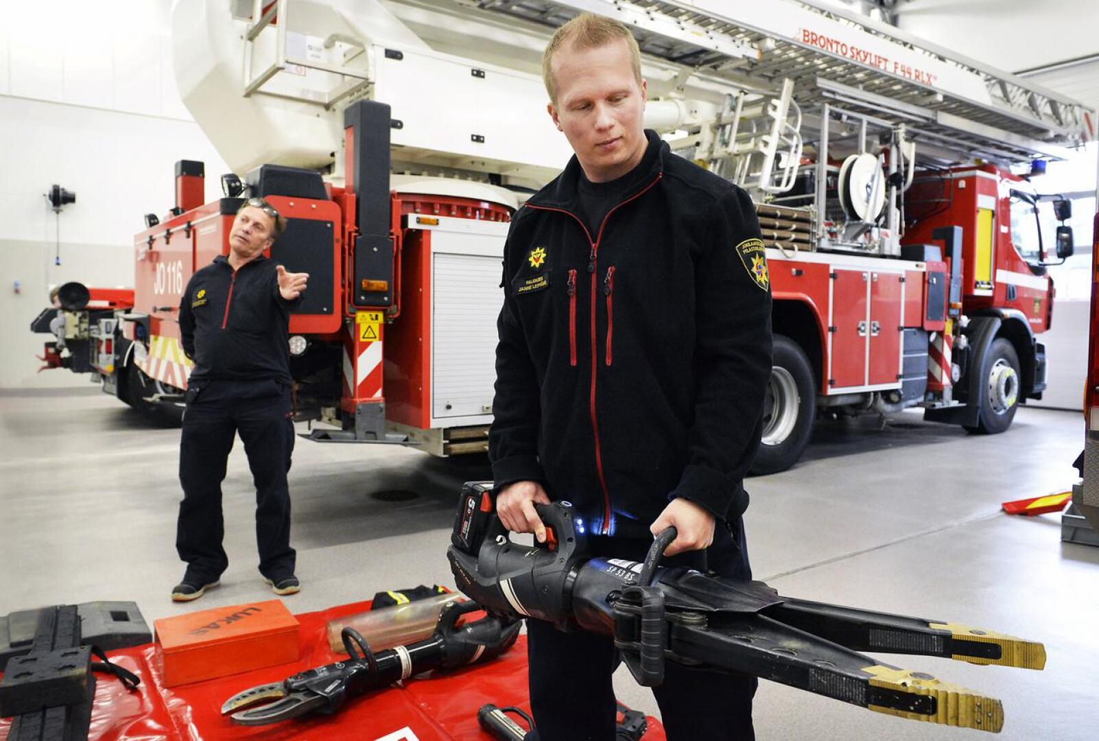 Tieliikenneonnettomuuksien vastuukouluttaja  Ari Tuulenkari  ja palomies Janne Leppänen esittelevät akkukäyttöisen hydraulisen levittimen toimintaa Haapajärven paloasemalla.